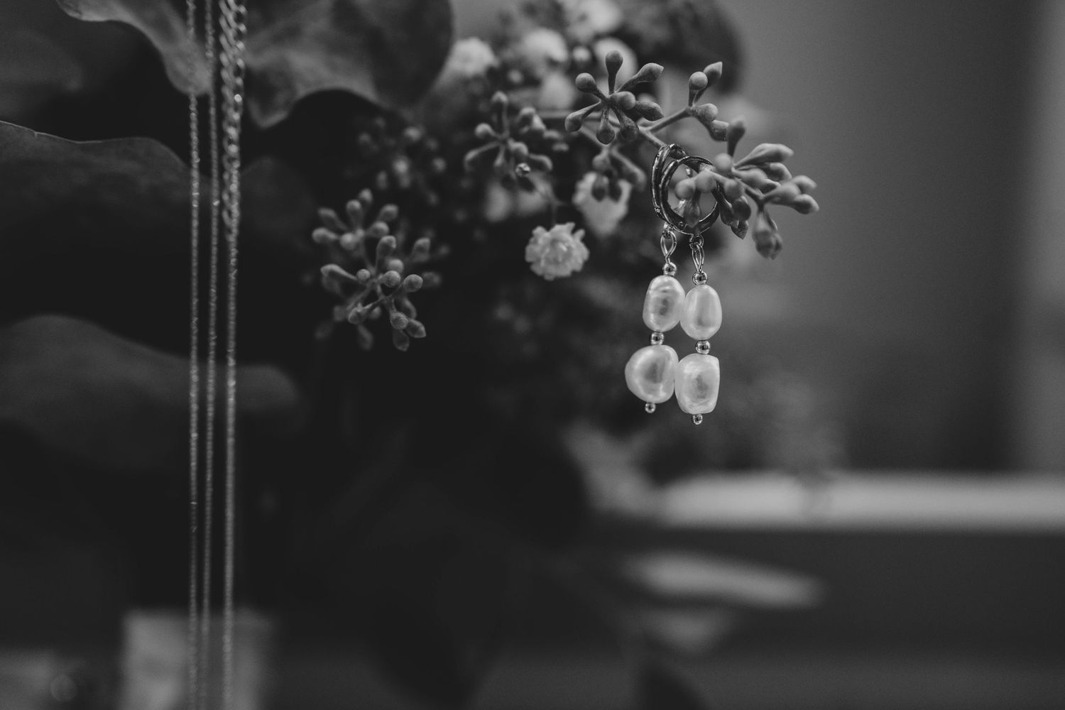 Black and white wedding ceremony photo showing floral arrangements and guests in formal attire.