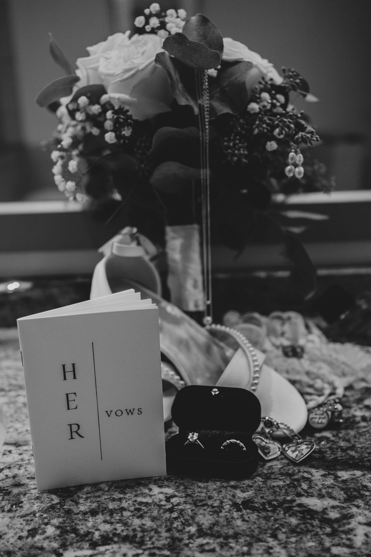 Black and white wedding detail shot showing small cards with letters and vows displayed among floral decorations.