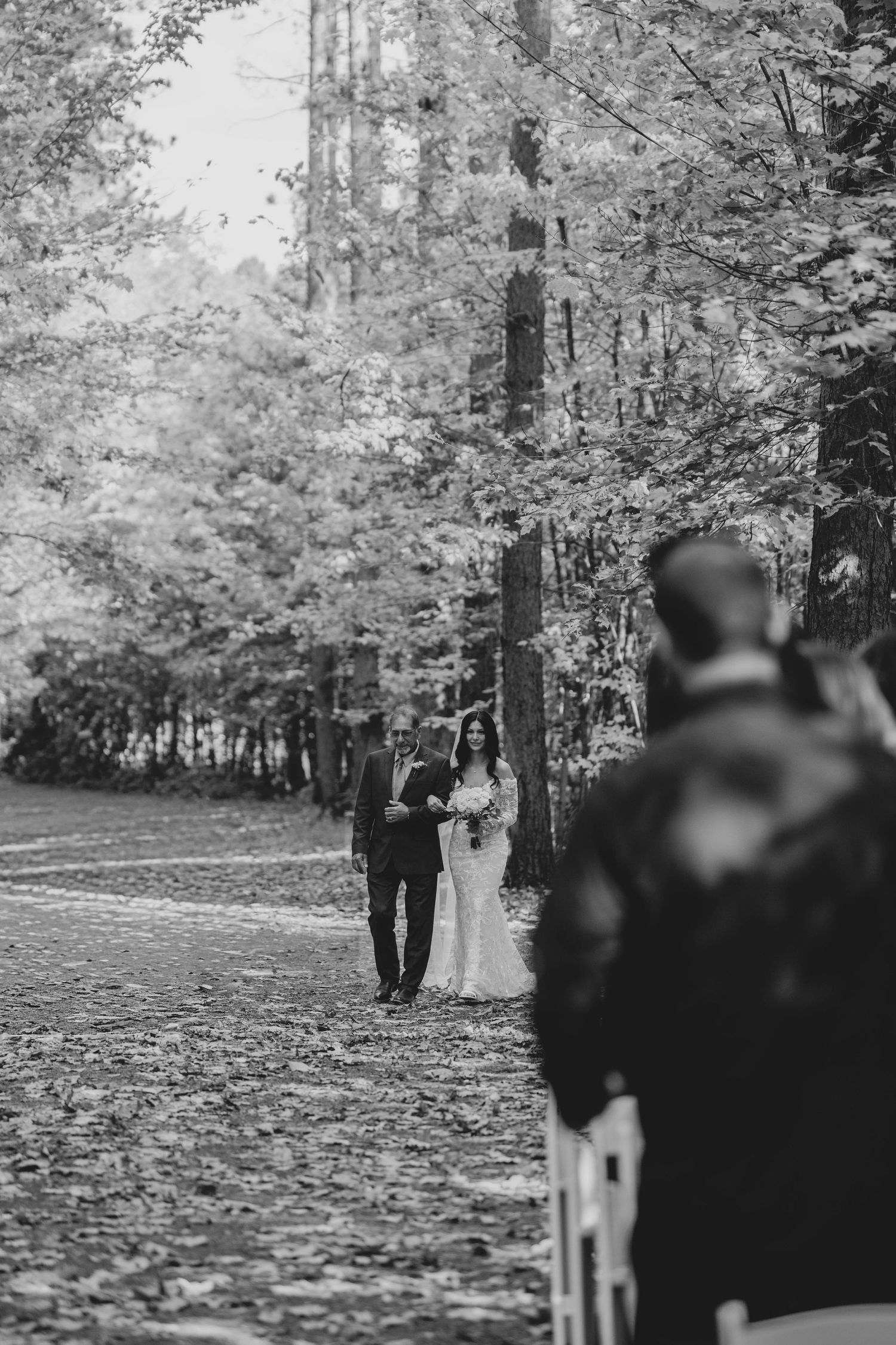 A romantic autumn wedding photoshoot in a park with fallen leaves covering the ground.