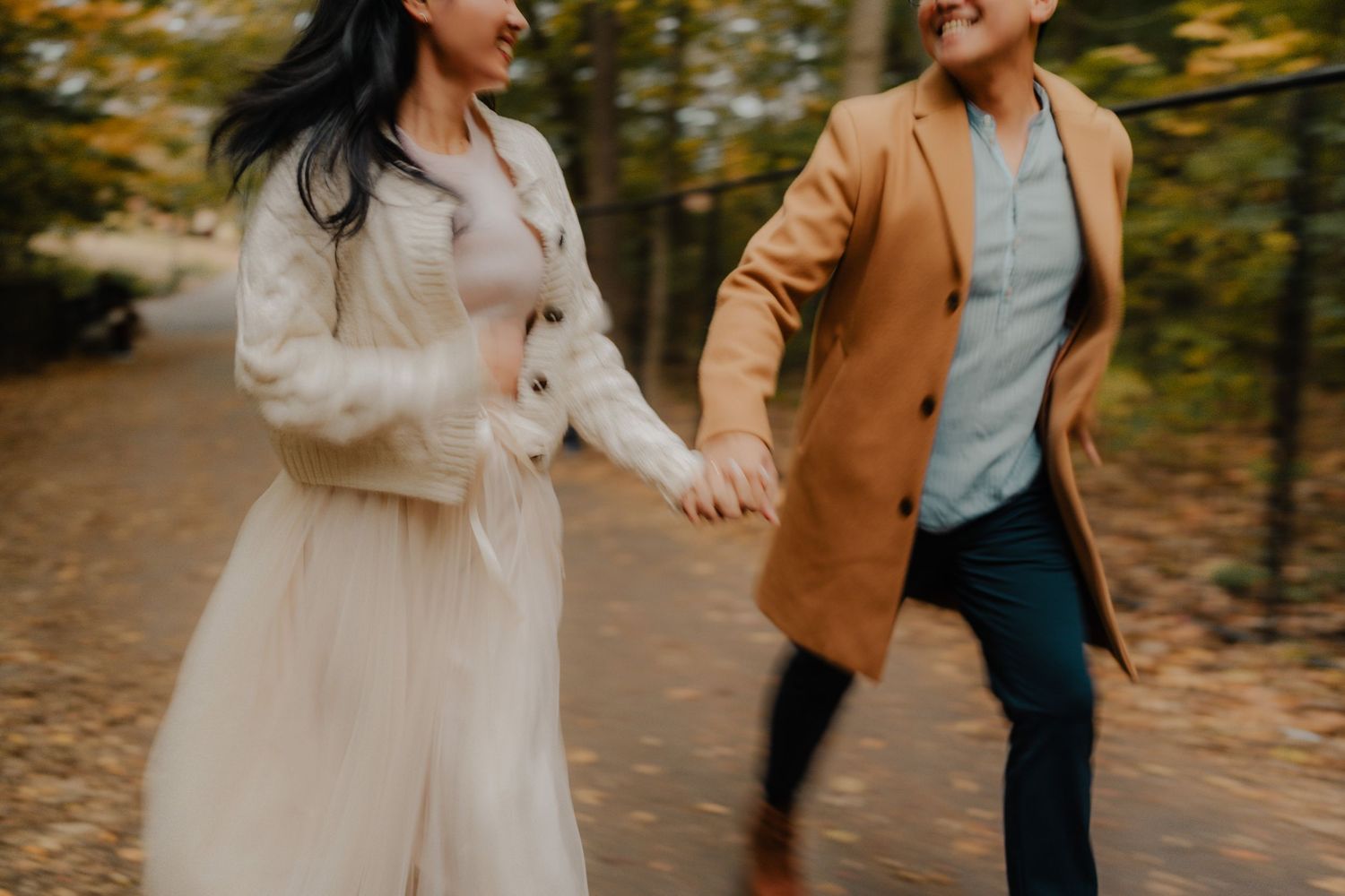 A couple walks together on a path surrounded by autumn trees with golden foliage.