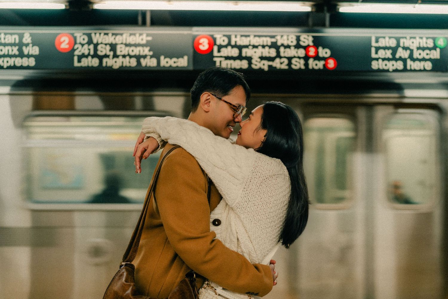 People waiting on a subway platform with fluorescent lighting and green accents in the background.
