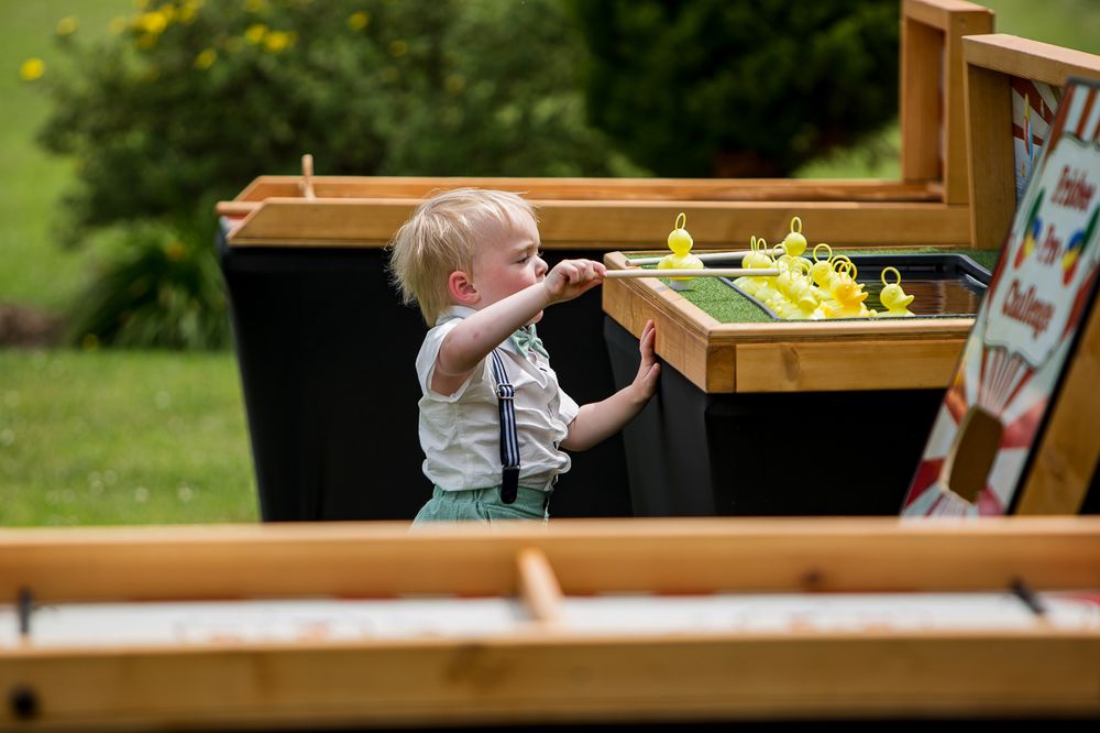 Children play at wooden activity tables during outdoor wedding reception.