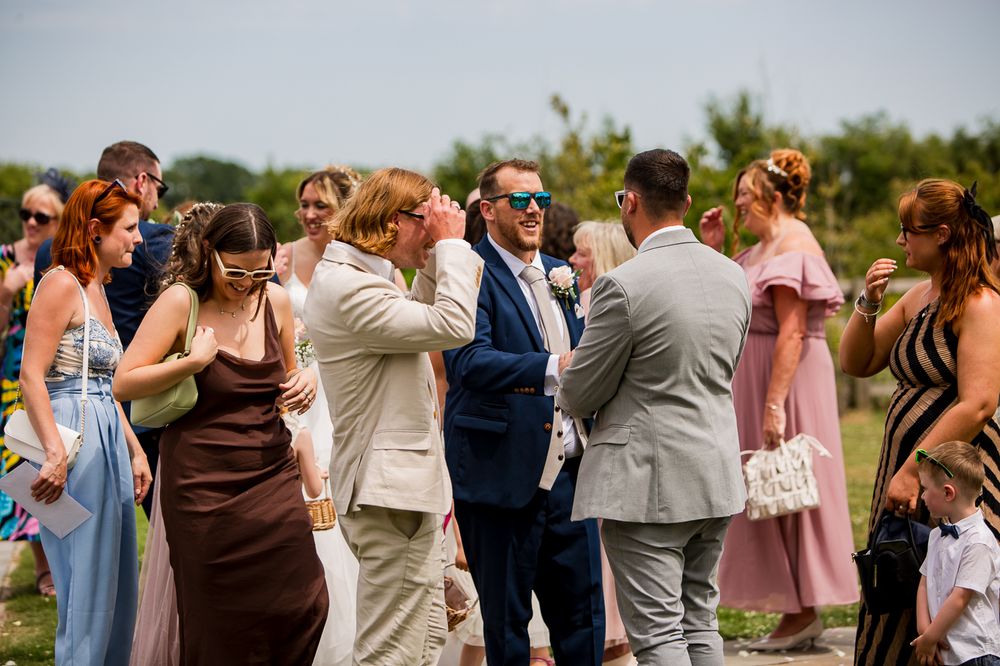 Wedding party and guests mingle during outdoor summer celebration.