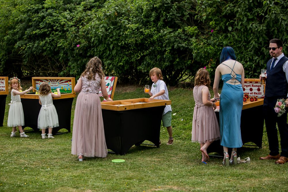 Wedding reception setup with rustic wooden tables in lush garden setting.