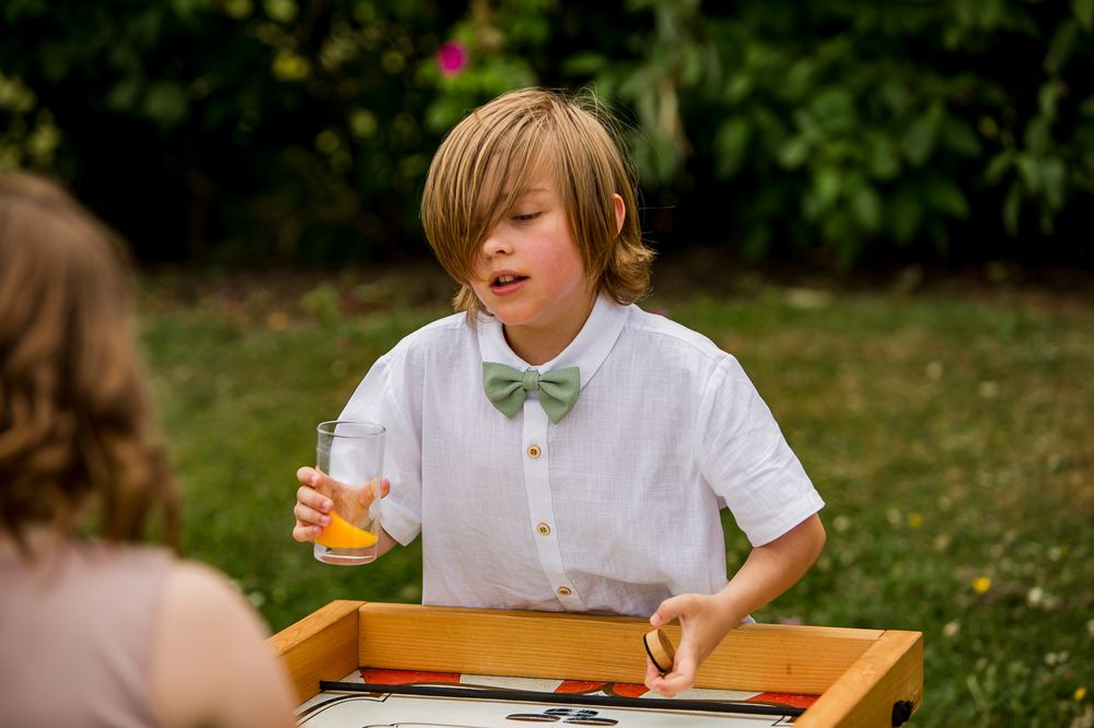 Outdoor wedding game setup showing wooden tracks and yellow balls on a grassy lawn.