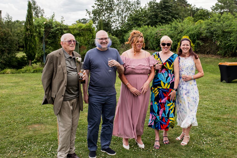 Guests in summer attire socializing on a lawn during an outdoor wedding reception.