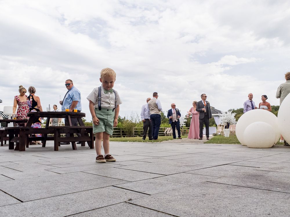 Wide angle view of wedding guests relaxing on outdoor decking during a reception.