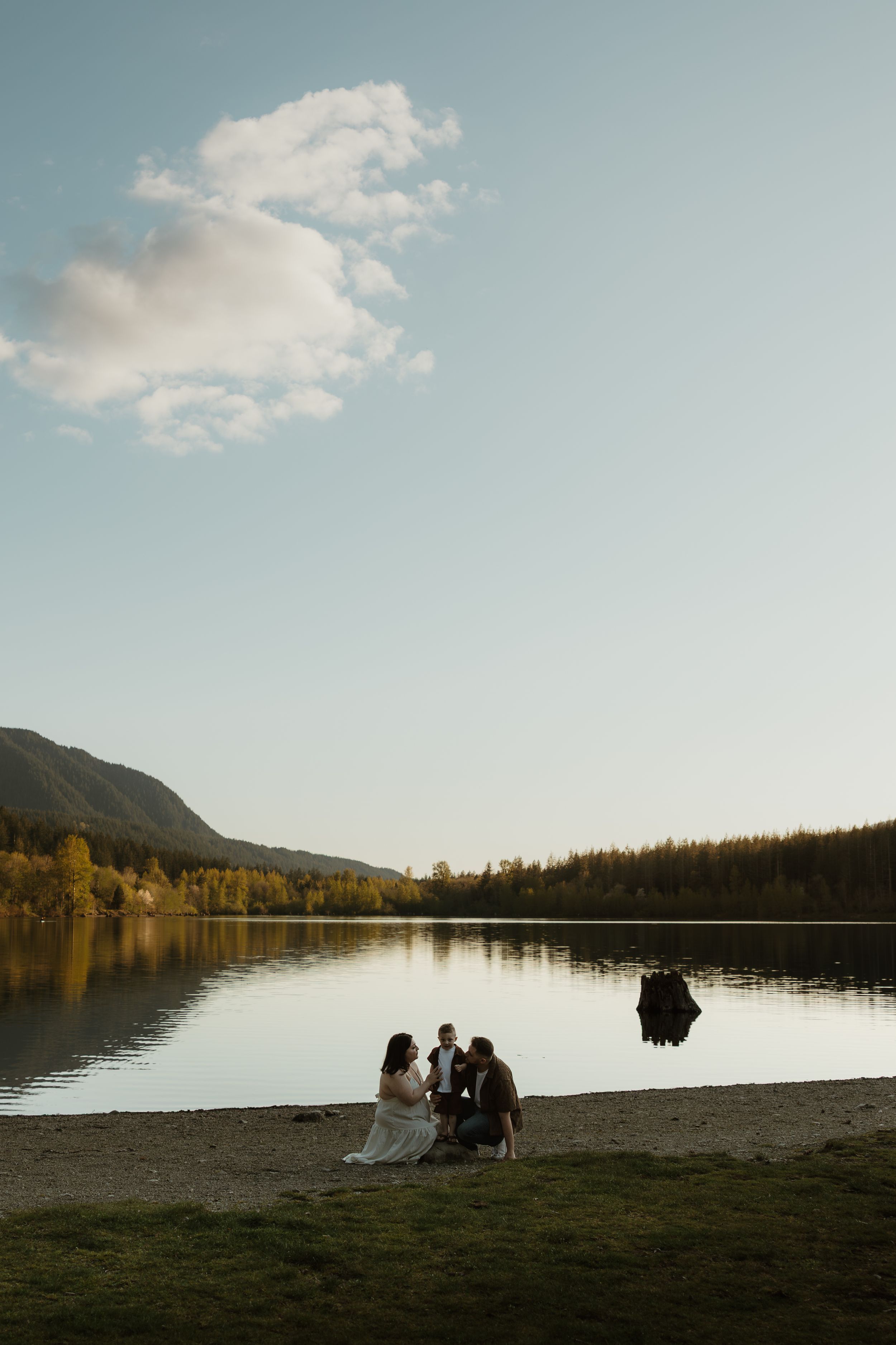 Scenic lakeside photo session with mountains and fall foliage in the background.
