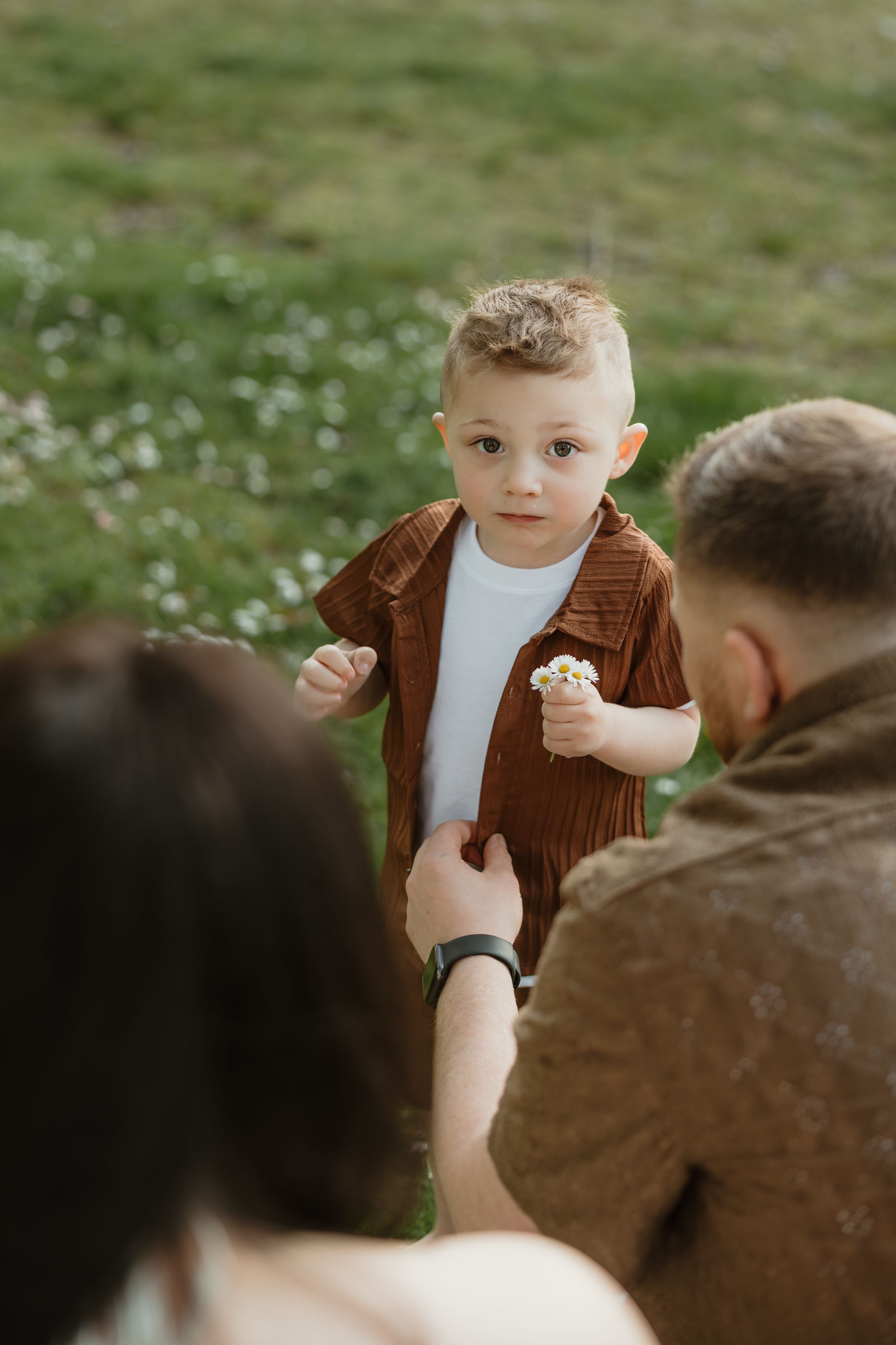 Small child in brown cardigan and white shirt plays outdoors in a candid sequence of photos.