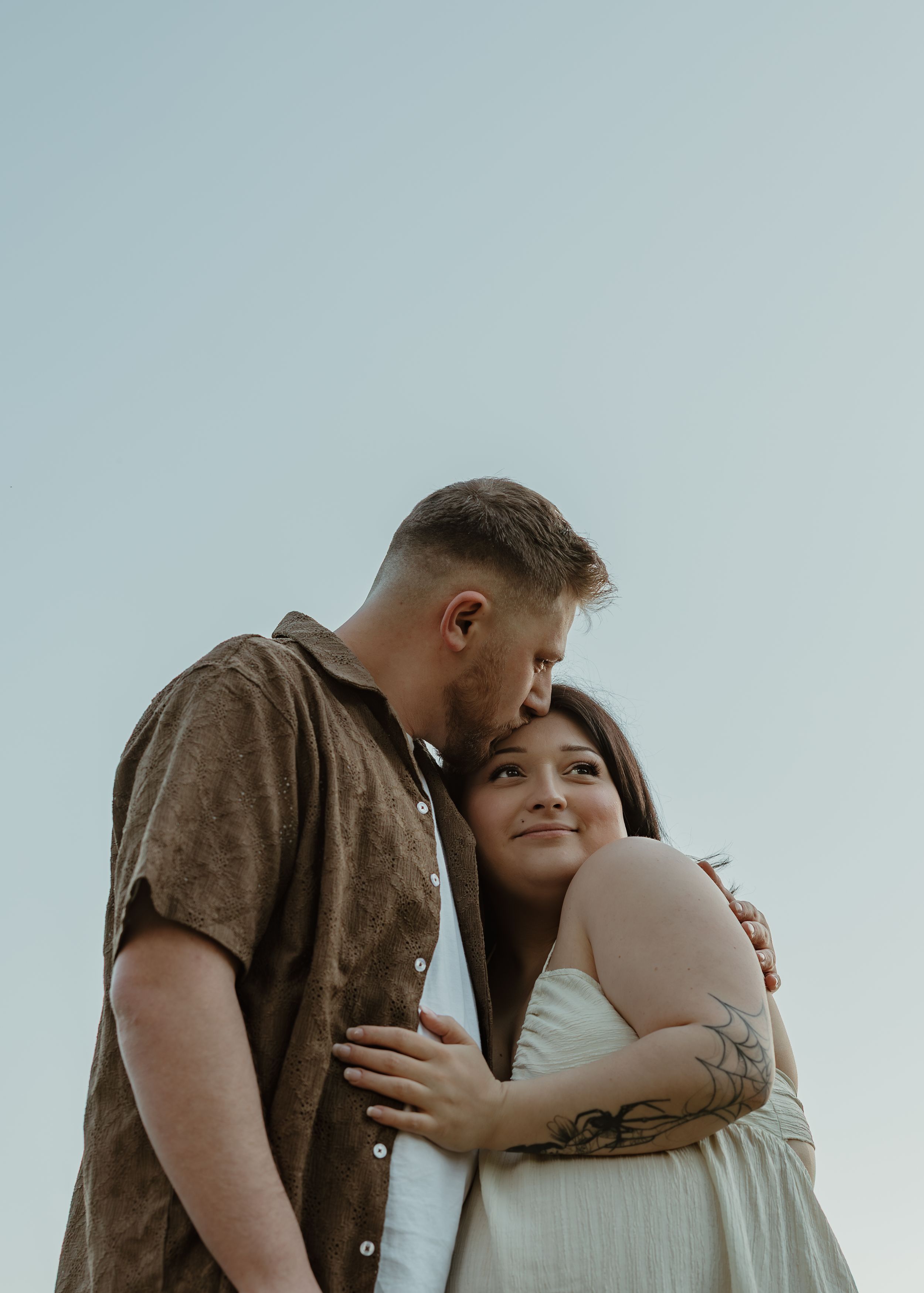 Intimate outdoor portrait session against a bright sky background.