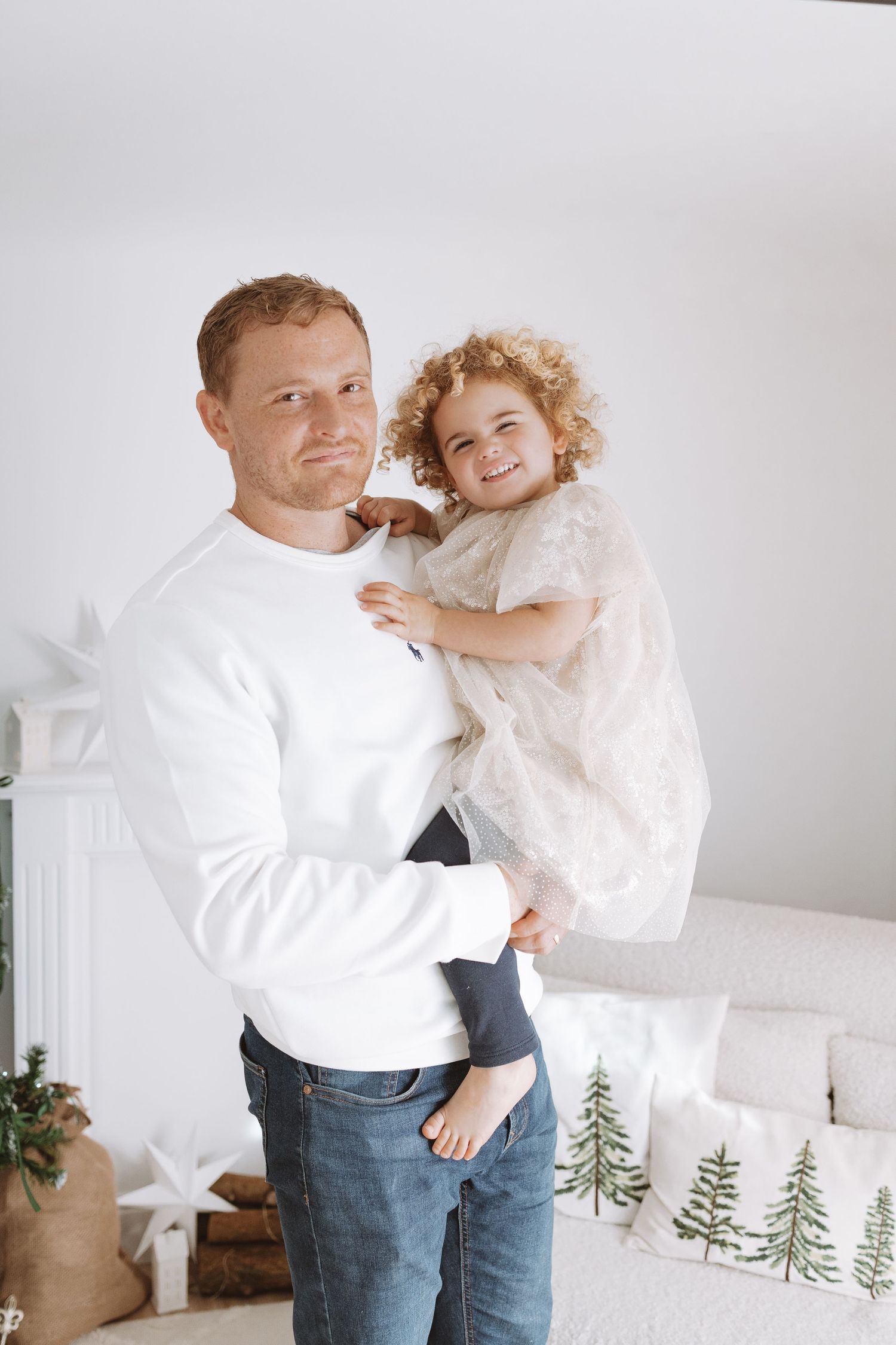 Parent and child in white shirts share playful moments together against a minimalist white background.
