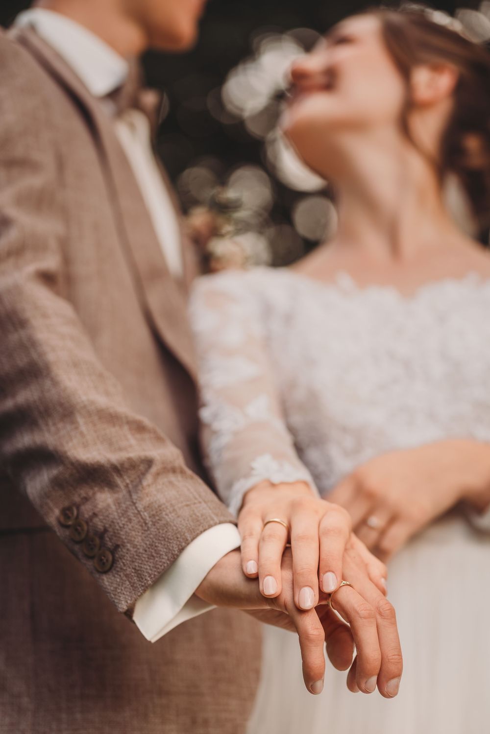 A close-up view of newlyweds' hands with wedding rings as they share an intimate moment together.