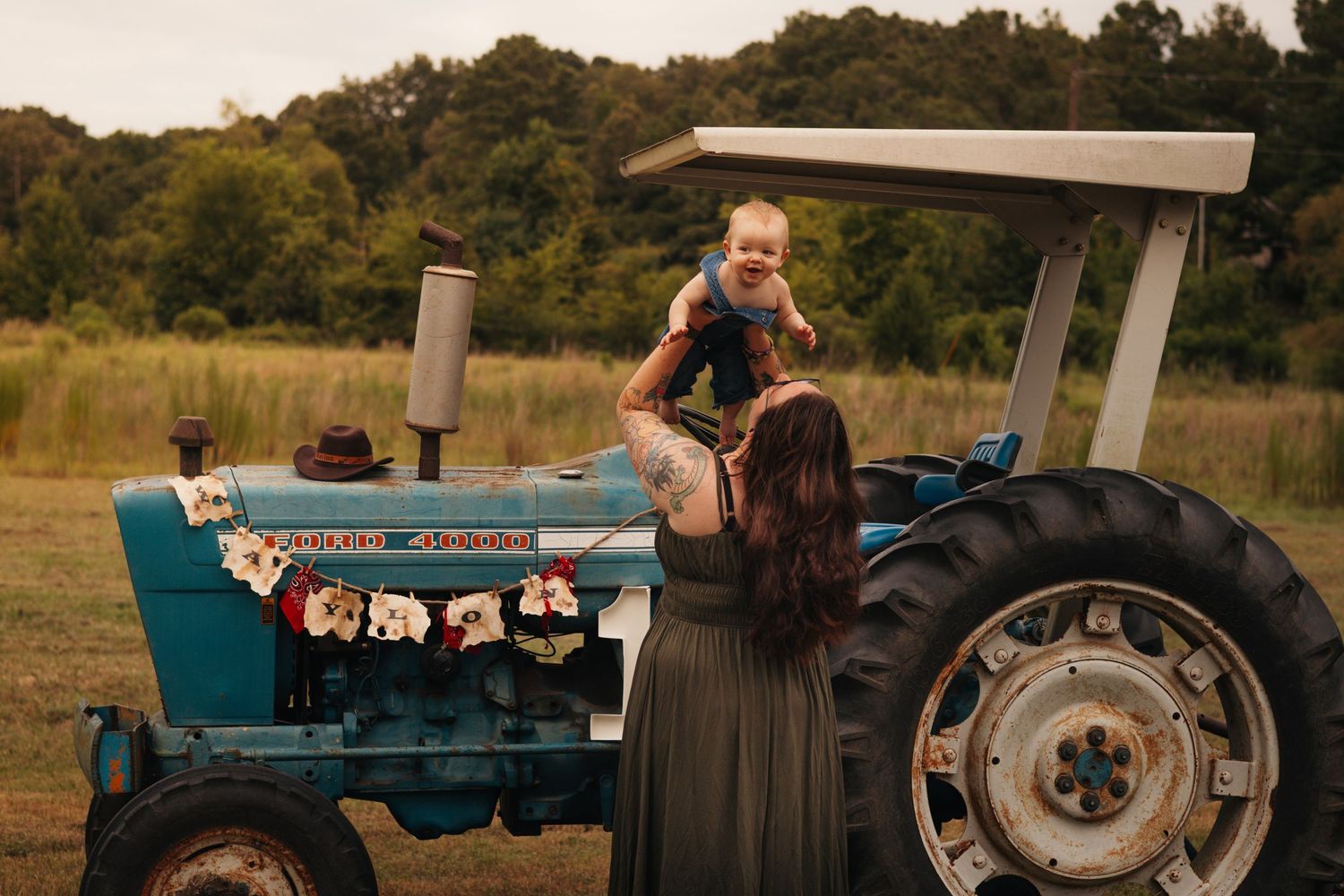 Young family spending time together outdoors beside a vintage tractor during a family photography session.