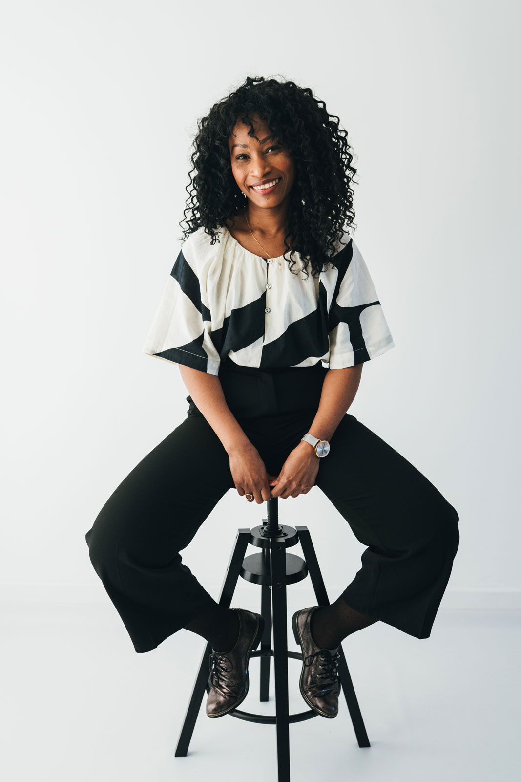 Photo corporate femme souriante en studio, assise sur un tabouret, portrait professionnel naturel