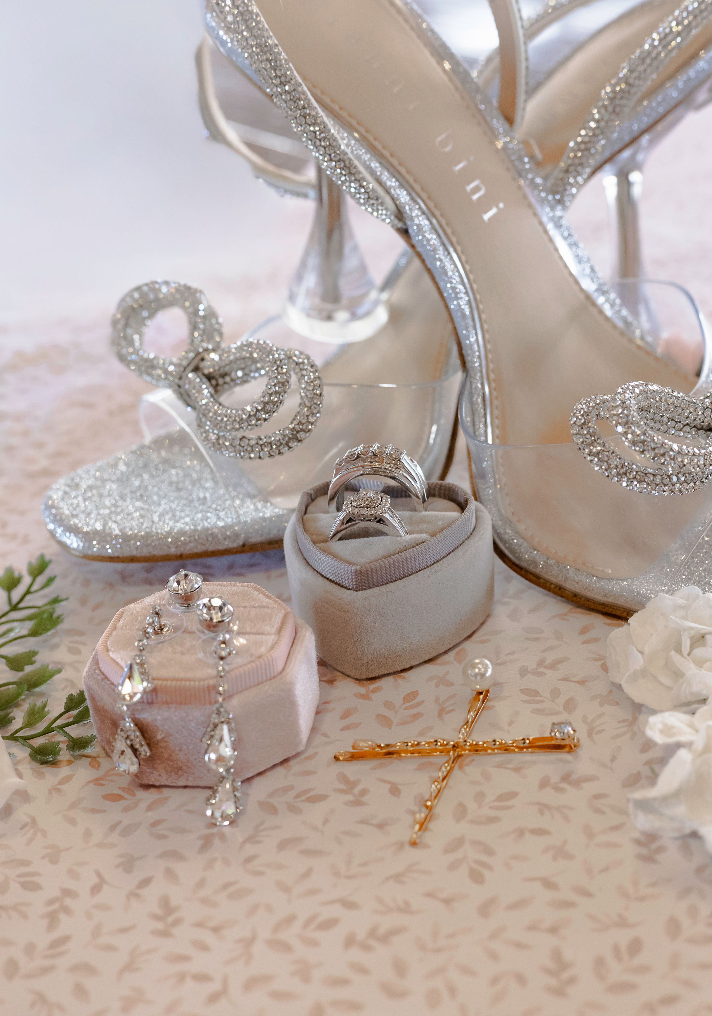 Elegant silver wedding shoes with crystal embellishments displayed on lace fabric.