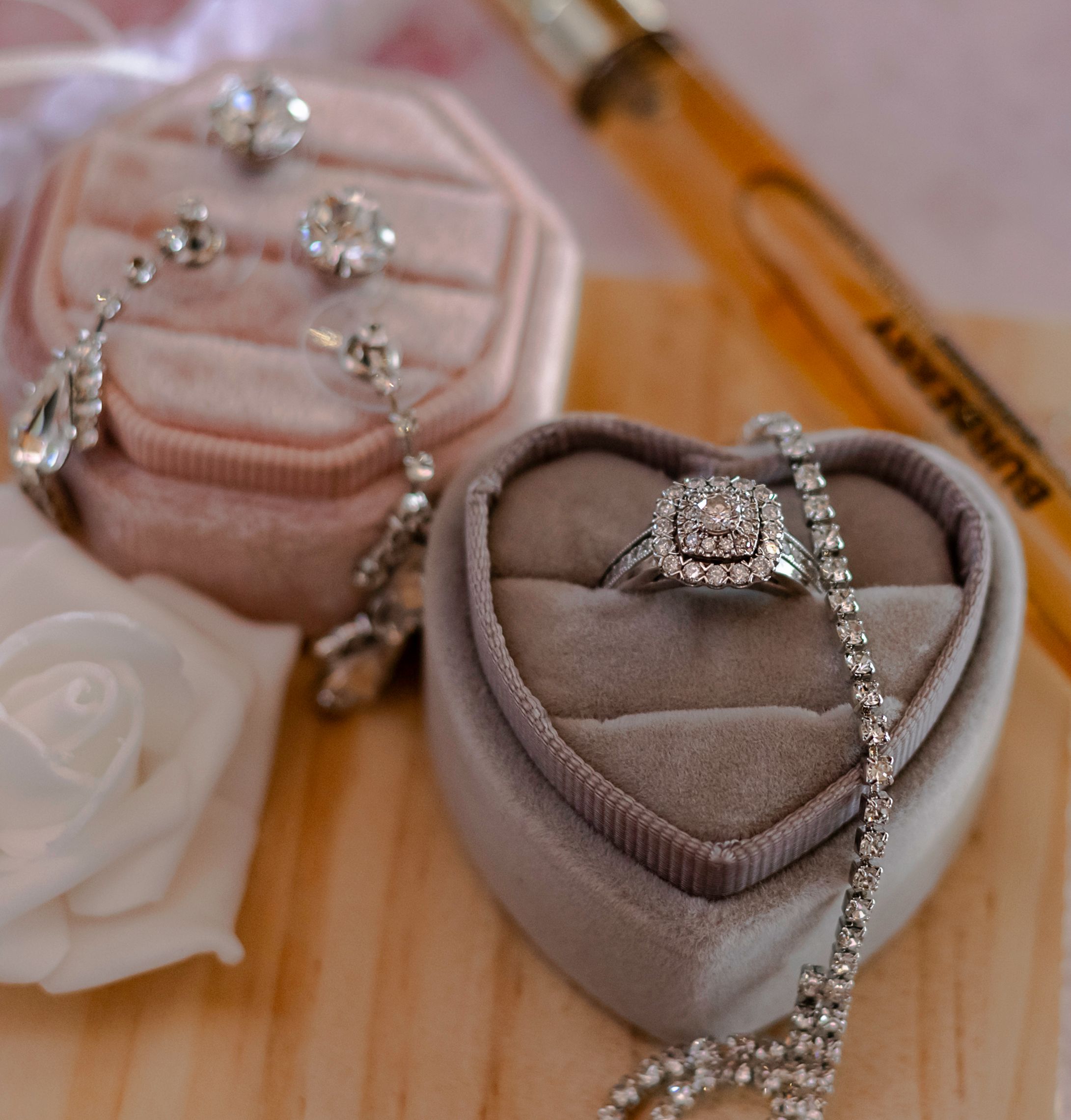 Delicate crystal bridal jewelry and accessories arranged on wooden surface.