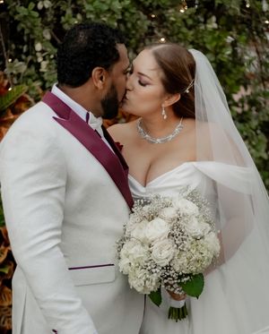 A couple sharing a romantic moment during their wedding ceremony with white floral bouquet details.