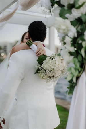 White floral arrangements and greenery decorate an elegant outdoor wedding ceremony setup.