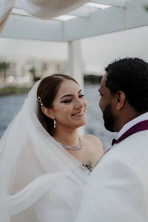 Intimate wedding ceremony moment captured under white draped canopy with floral details.