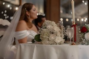 Romantic reception setting with string lights and white floral centerpieces at dusk.