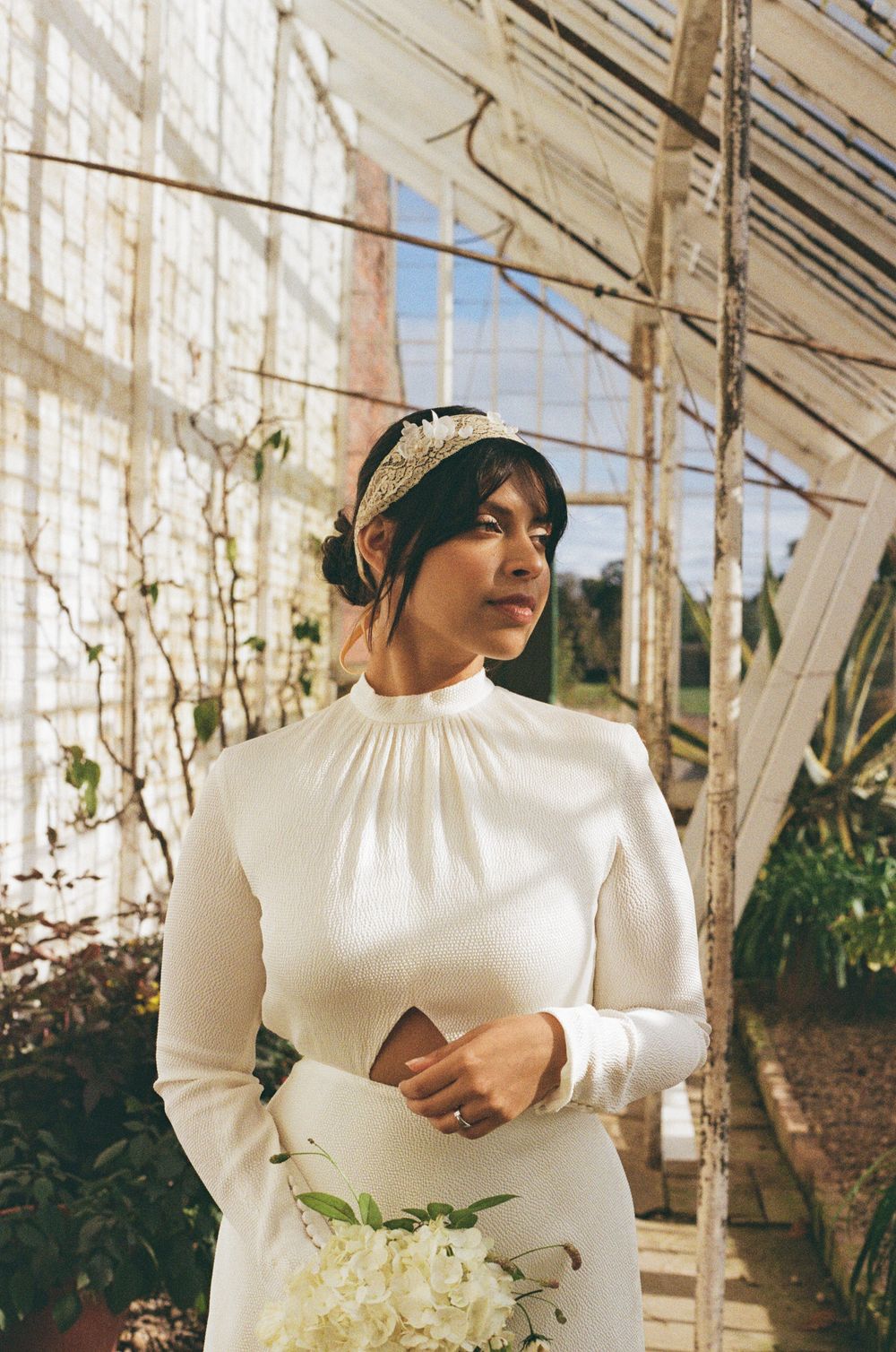 nostalgic wedding film moment in a sunlit greenhouse setting with hanging vines.