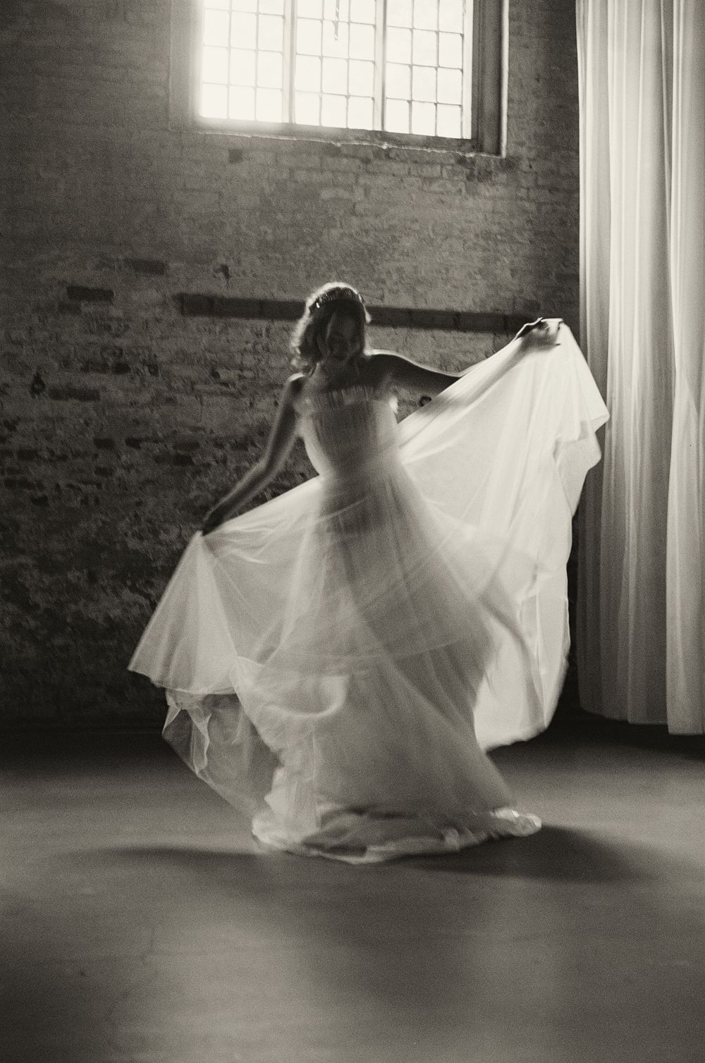 35mm film wedding portrait white wedding dress twirls in an industrial loft space with brick walls and natural light.