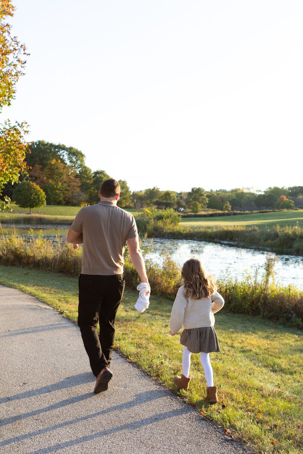 People walking along a scenic path next to a lake during sunset.