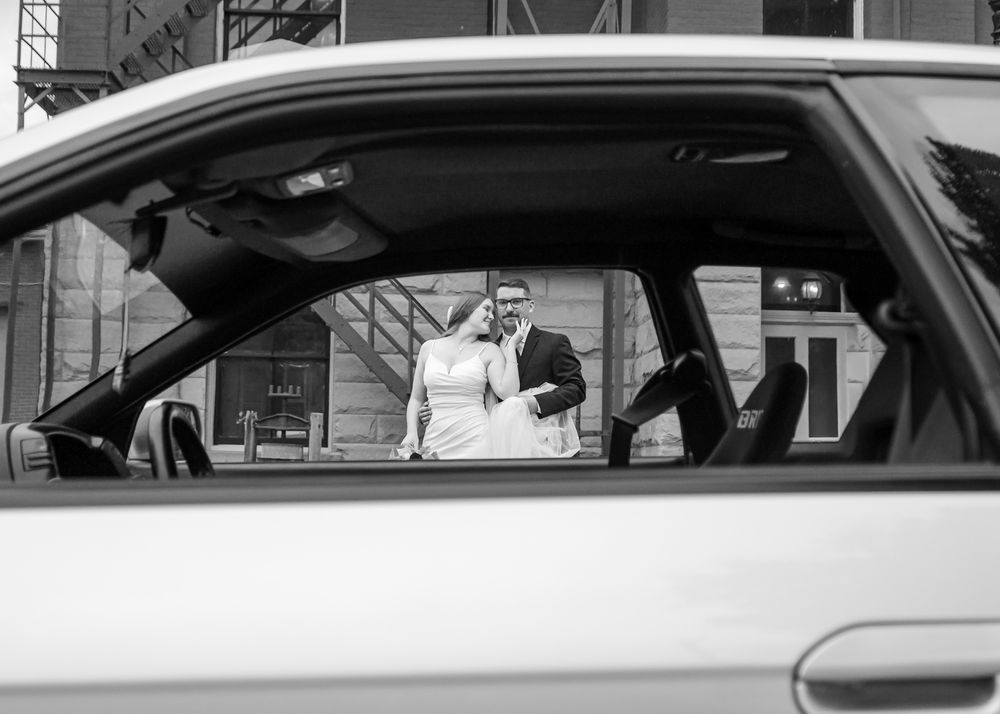 Black and white photo of luxury cars parked in a row at a wedding venue.