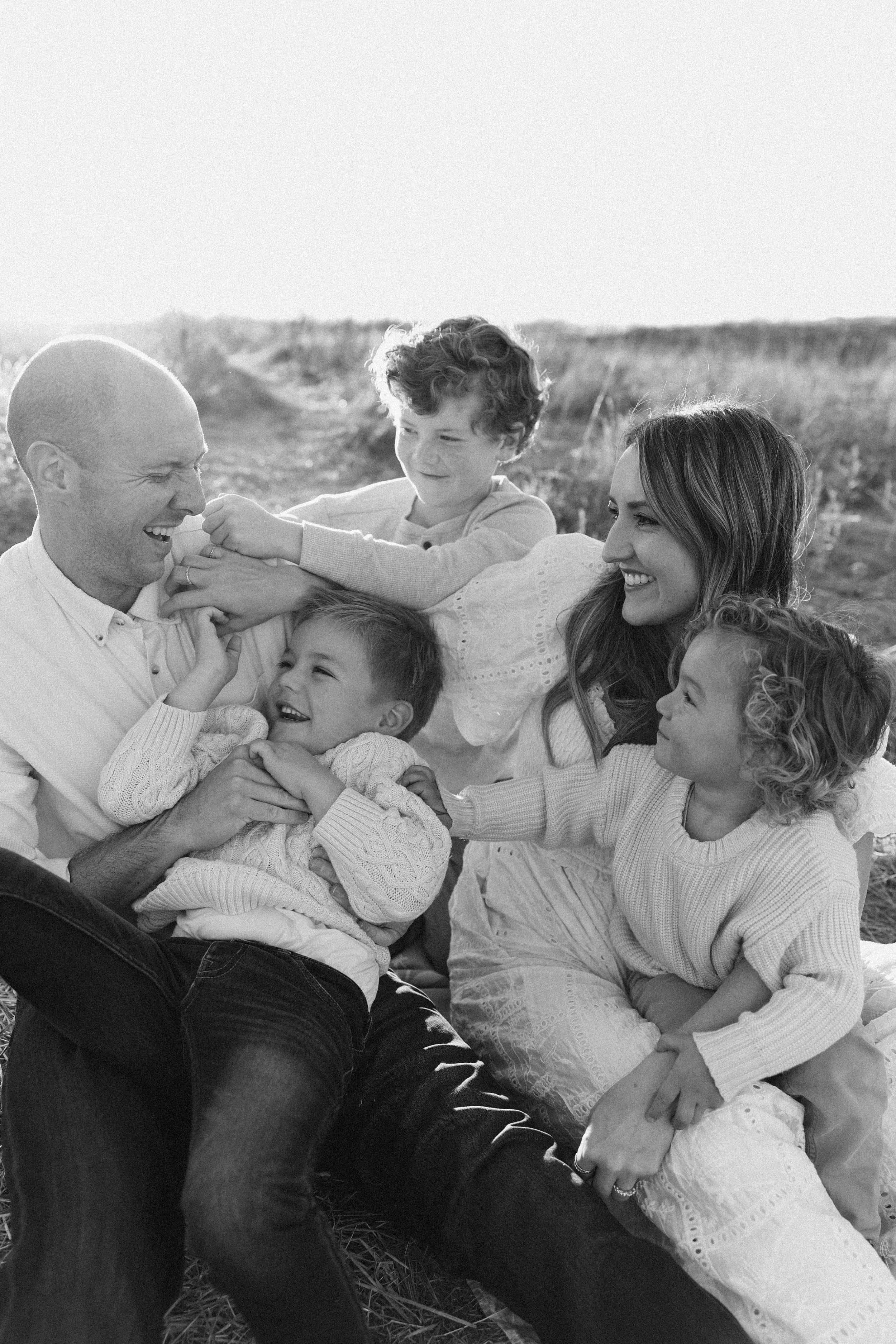 Family of five sitting in tall grass during sunset Orange County family photoshoot