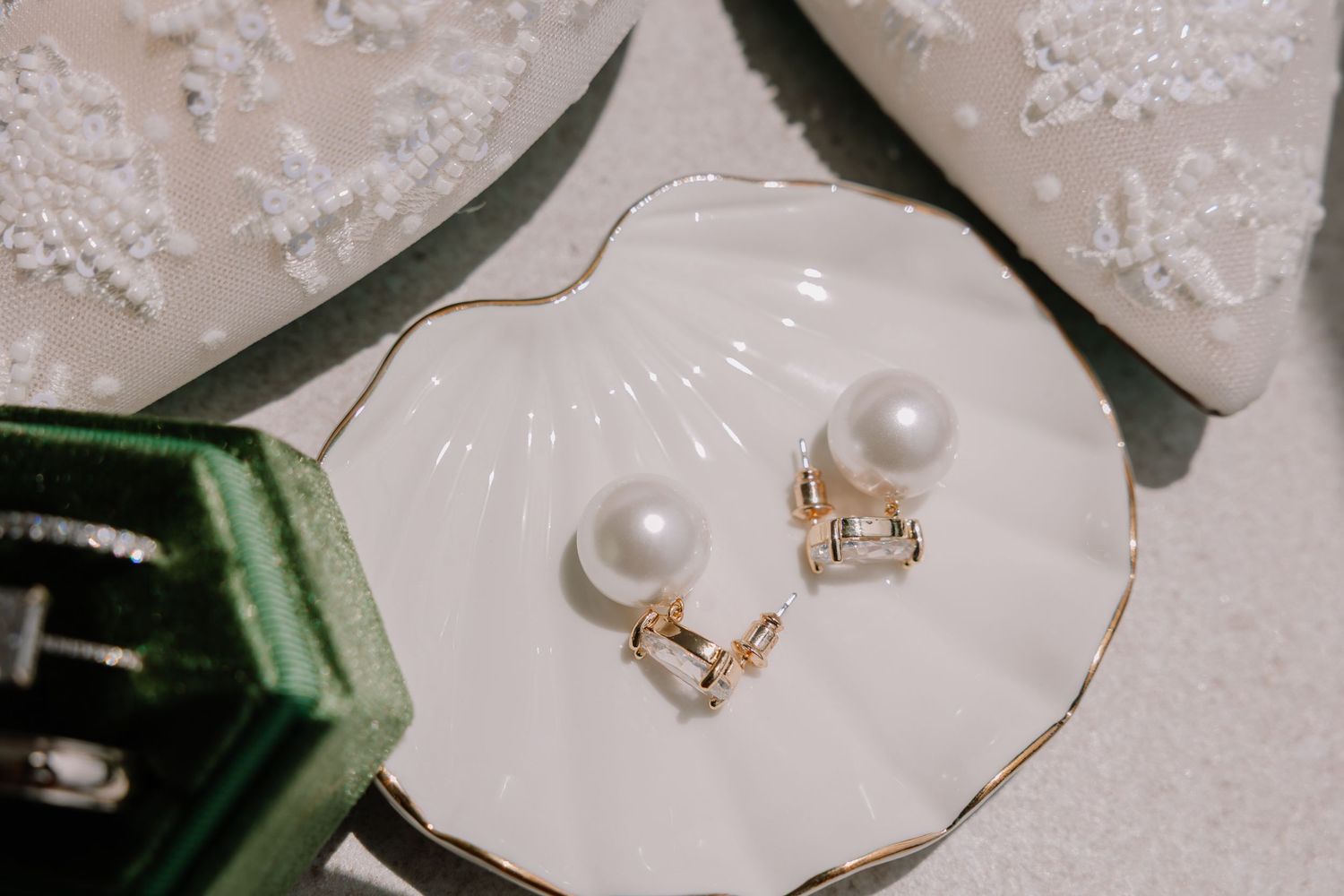 Delicate pearl earrings and jewelry details on a white lace background.