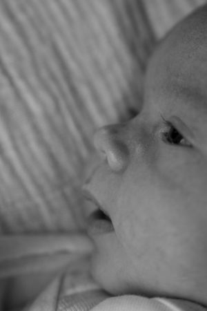 Close-up black and white portrait of a peaceful newborn baby lying down, showcasing delicate facial features.