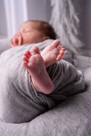 A series of close-up shots showing tiny baby feet resting on soft gray fabric.