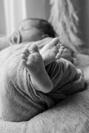 A series of black and white close-up photos showing a baby's tiny hand resting on soft fabric.