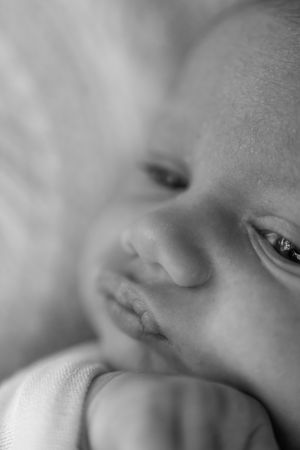 Close-up black and white portrait of a peaceful sleeping newborn baby with delicate features.