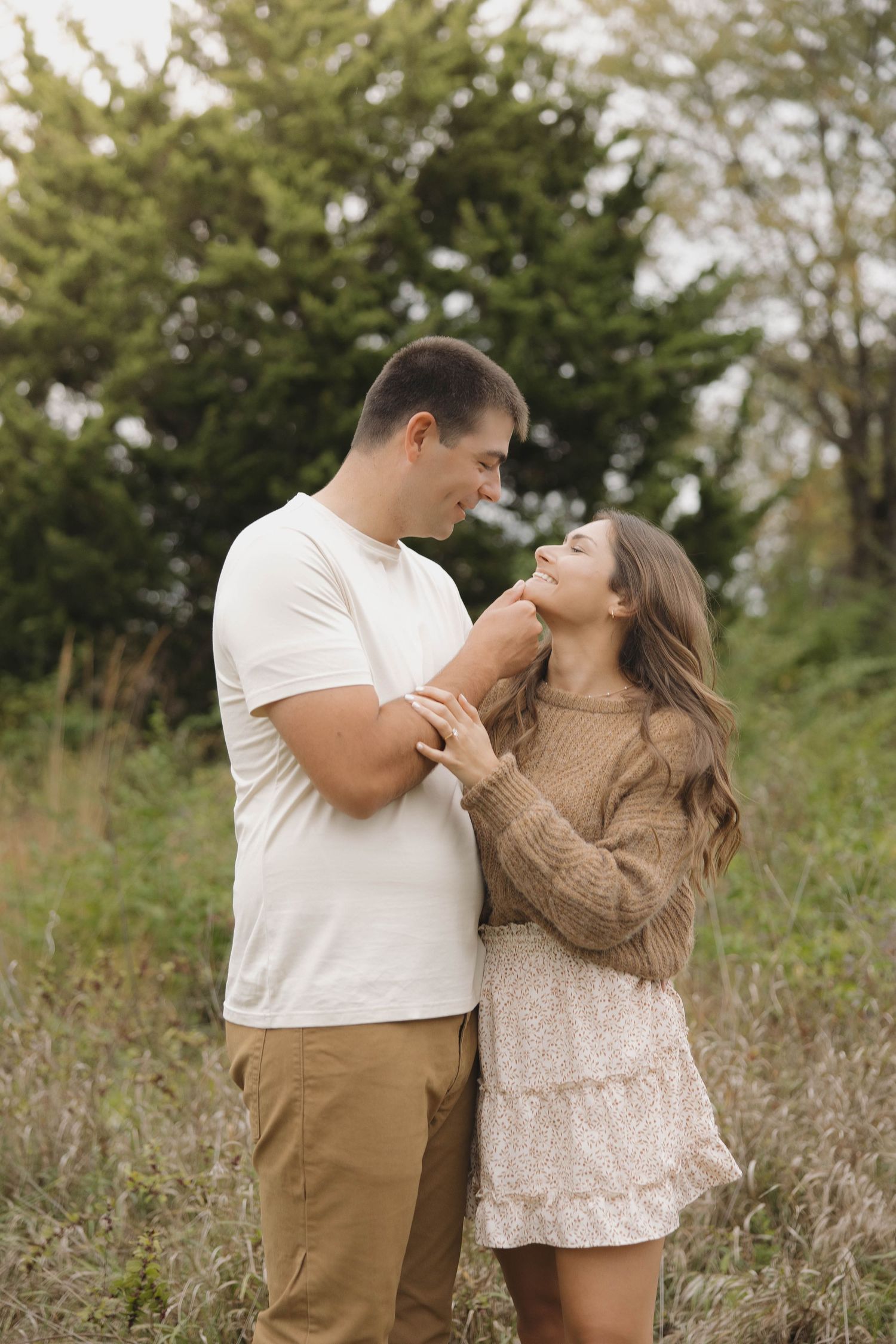 A couple shares playful moments together in a natural outdoor setting with greenery.