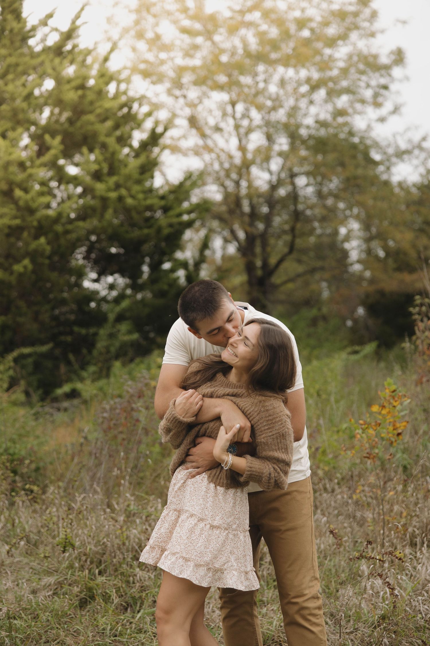 Two people share intimate embraces in a wildflower meadow during golden hour.