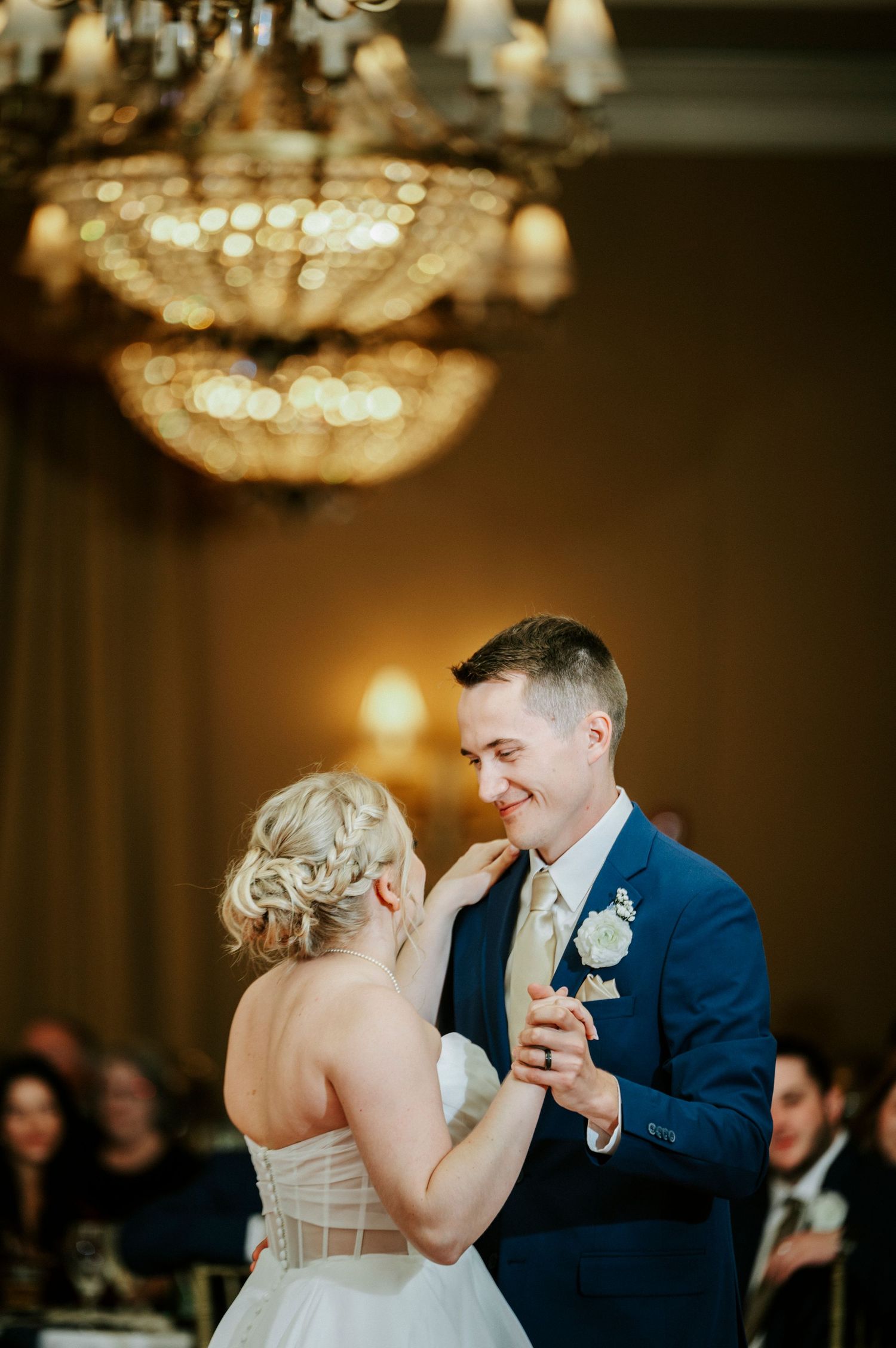 A romantic first dance at an elegant ballroom wedding reception under crystal chandeliers.