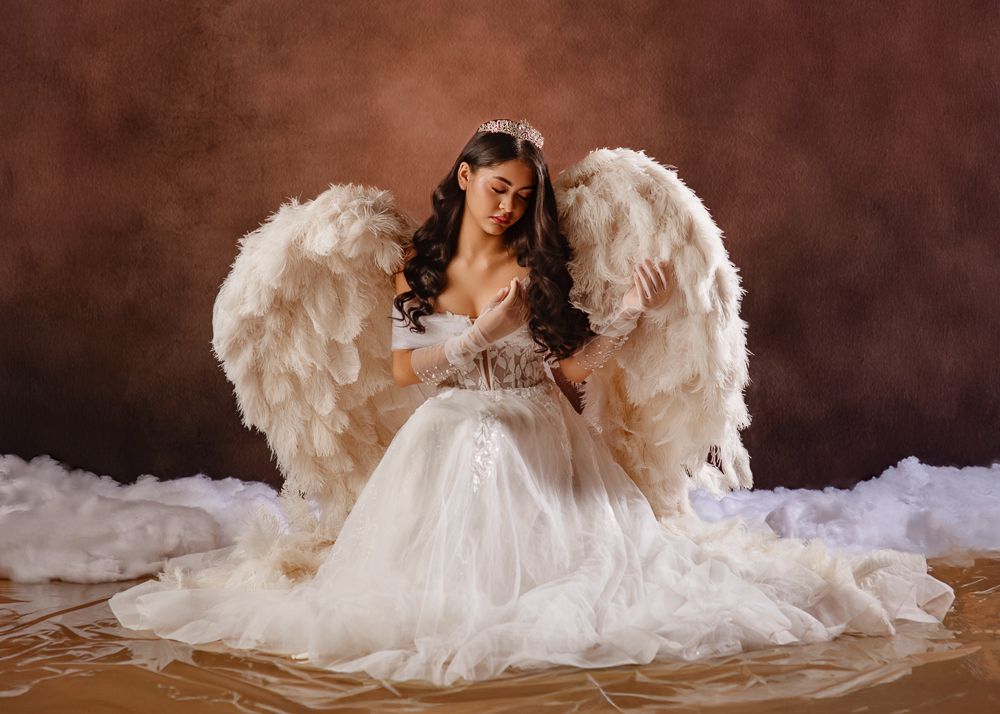 A flowing white wedding dress with ruffles and lace details creates a romantic silhouette against a dark background.