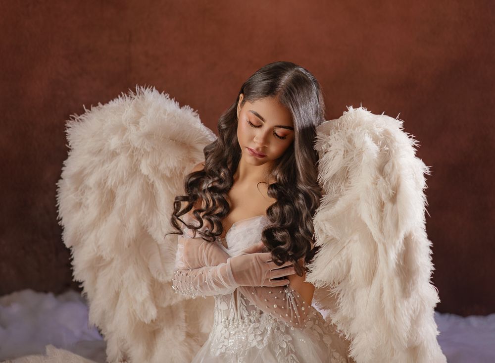 Series of romantic maternity portraits showing flowing white dress and angel wings in moody brown studio setting.