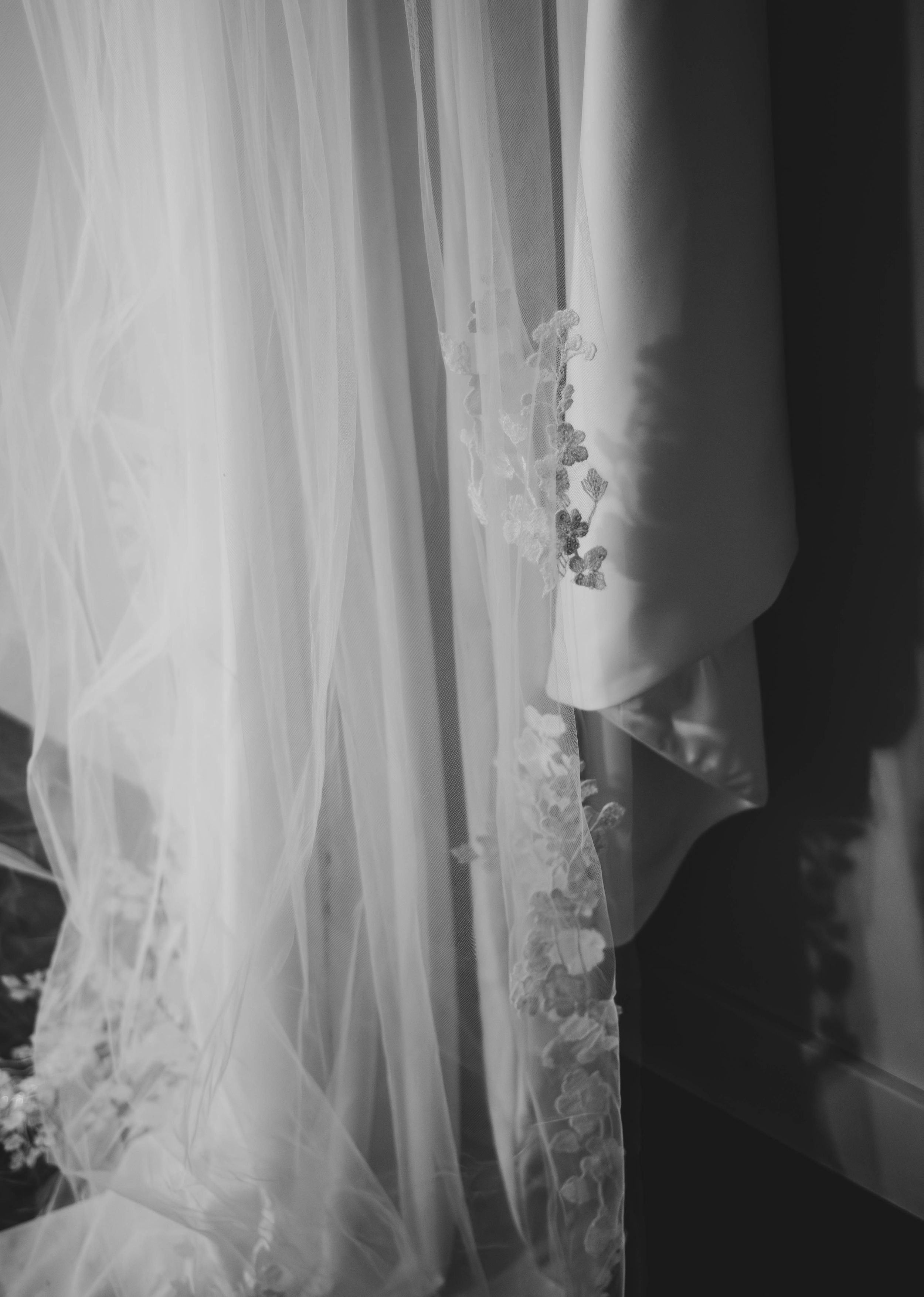 Close-up black and white detail of delicate lace and tulle wedding veil fabric.