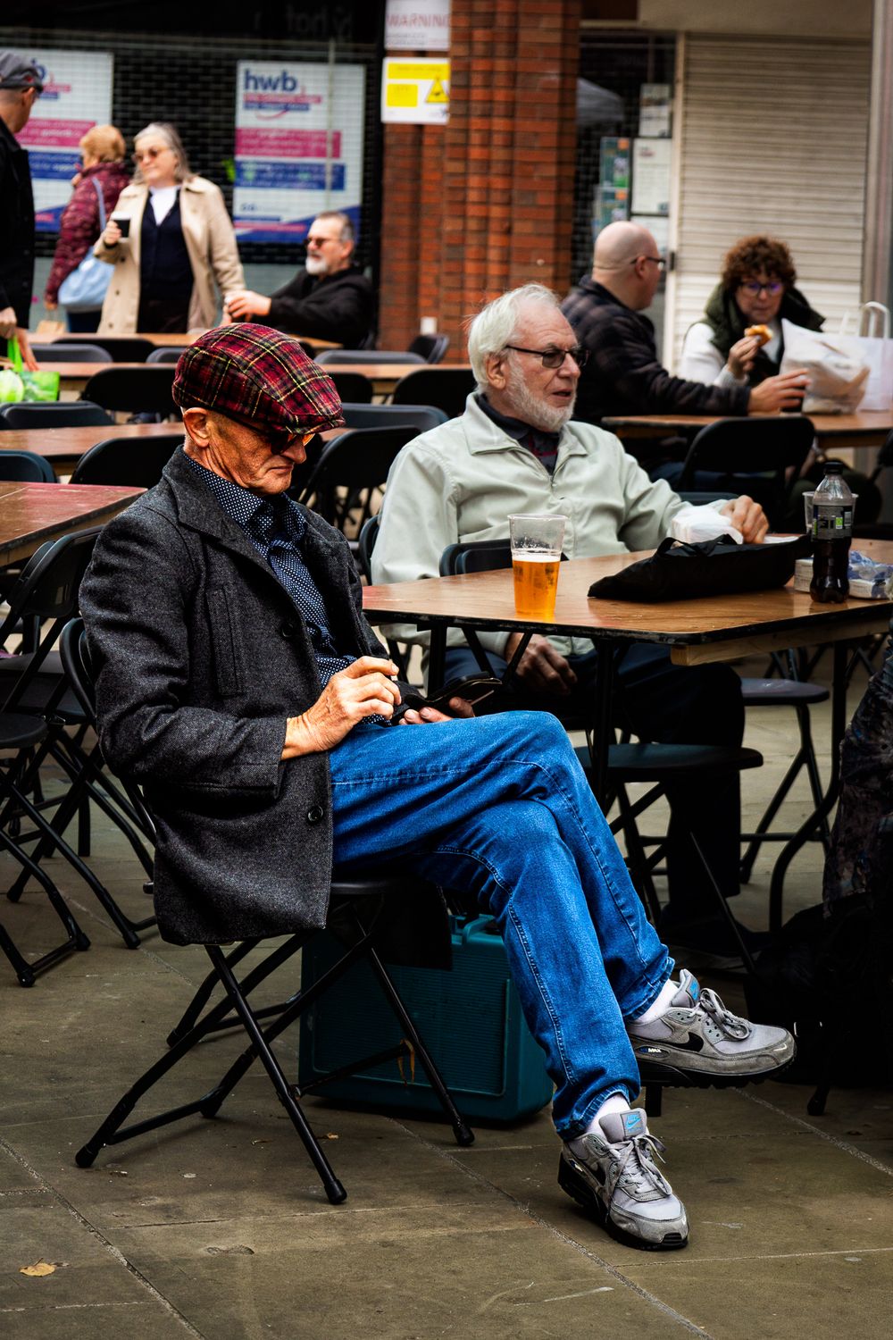 People sitting on folding chairs in a community space with brick walls and tables.