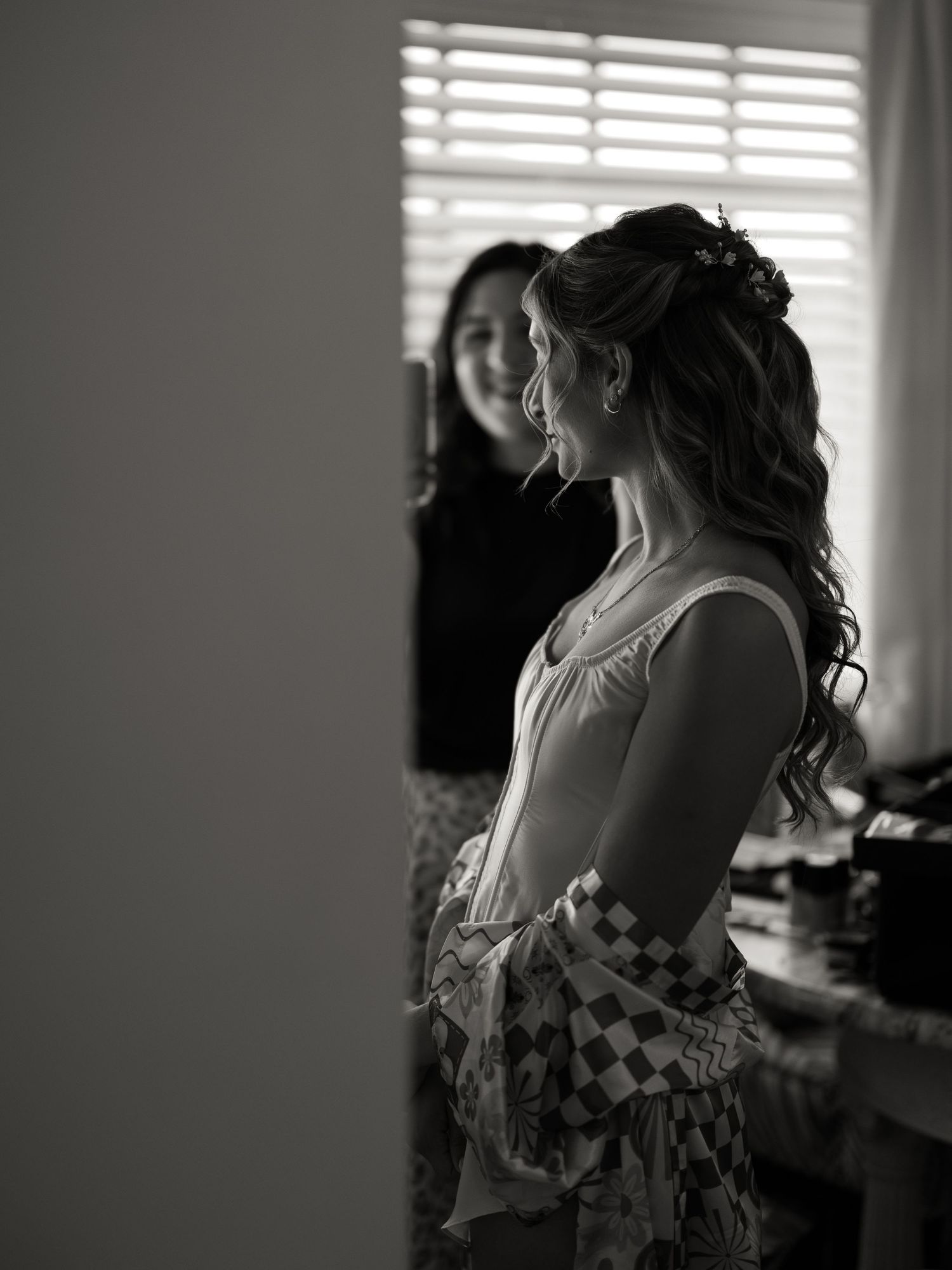 Silhouetted figures prepare for a wedding against window light in a getting ready room.