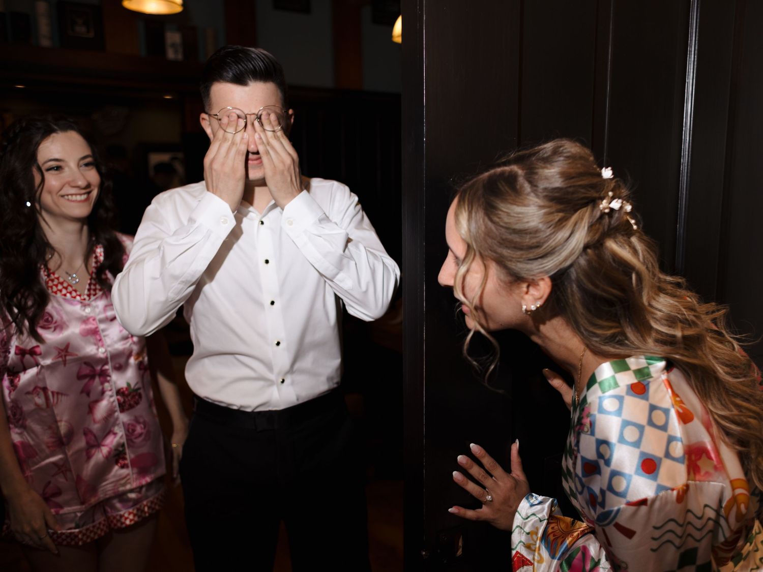 Wedding guests dance and celebrate together on a dimly lit dance floor at a reception party.