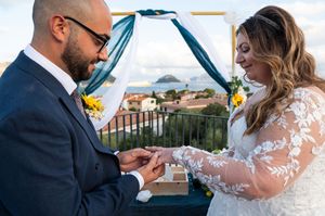 Wedding ceremony participants share intimate moment while exchanging vows outdoors.