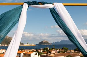 White fabric draping against blue sky with coastal landscape in background.