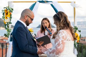 Couple holding hands during wedding ceremony with sunflowers and citrus decor.