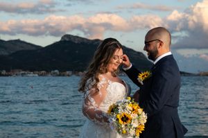 Romantic waterfront wedding photos with dramatic cloudy sky.