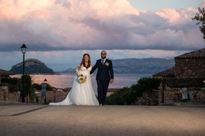 Panoramic view of wedding couple on stone terrace with coastal mountains.