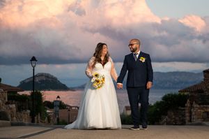 Wide landscape shot of wedding celebration with Mediterranean coastal scenery.