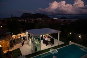 Evening reception panorama with pool and coastal mountains in background.